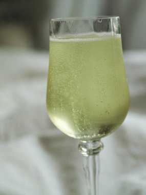 Beyaz bir battaniyenin üzerinde beyaz bir şarap bardağının yakın çekimi.