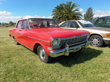 Eski kırmızı Chevrolet 400 Chevy II 4 kapılı sedan 1960 'lar GM Arjantin kırsalında. Doğa, çimen, ağaçlar. Klasik araba şovu..