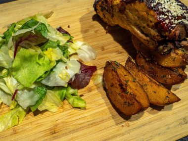 Kaburga, patates ve salatayı ahşap tabakta bir kenara koy.