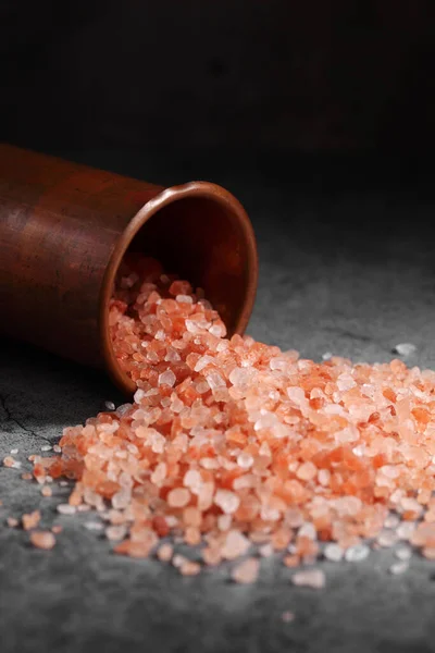 Fresh Himalayan pink salt scattered on the kitchen table from copper cup