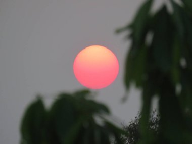 Kızıl güneşin büyüleyici bir görüntüsü manzaranın üzerinde