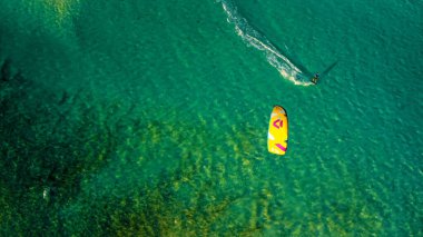 Okyanusun sakin sularında tek başına sörf yapan bir uçurtma sörfçüsünün hava aracı görüntüsü.