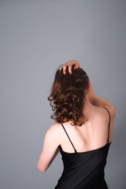 Gri bir duvara karşı poz veren bir kızın yakın çekimi.