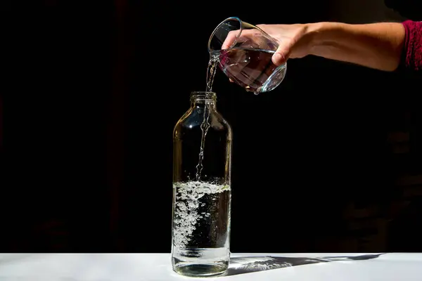 Gros Plan Une Main Versant Eau Verre Dans Une Bouteille — Photo