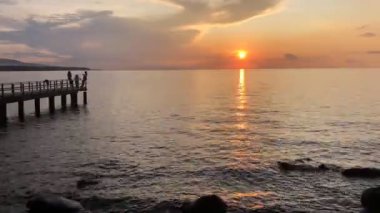 Gün batımında tekneye binen insanlarla deniz manzarası.