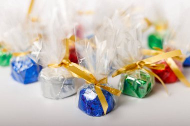 Beyaz arka planda altın bir kurdeleyle güzelce sarılmış renkli şekerlerin yakın plan çekimi.