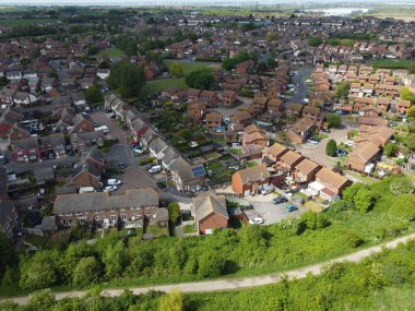 Yeşil bitki örtüsüyle çevrili kahverengi evleri olan yerleşim alanının yüksek açılı görüntüsü..