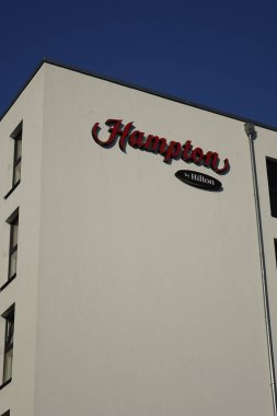 Hampton 'ın sol üst köşesinde Hilton Oteli, Beyaz Saray Duvarı, kırmızı ve kahverengi yazılar, açık mavi gökyüzü