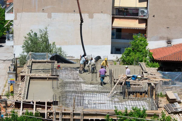 İnşaat işçileri, şehir merkezinde ev inşaatı. Beton ve beton döken özel bir tekerlek makinesinin yardımıyla. Volos Şehri, Yunanistan