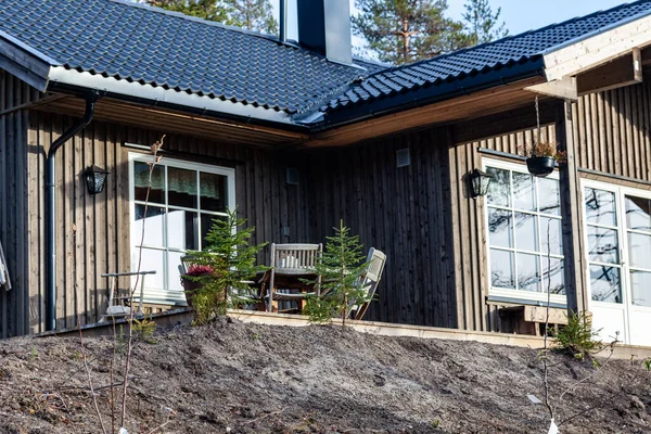 Terası ve küçük köknar ağaçları olan ahşap bir kırsal binaya yakın çekim.