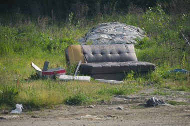 Yol kenarında bırakılmış eski bir kanepe ve karton kutular.