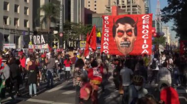 İnsanlar, güneşli yaz gününde Başkan Jair Bolsonaro 'nun hükümetine ve Avenida Paulista' nın kamu politikalarına karşı posterlerle protesto ediyor. 4K
