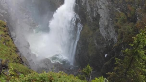 一片迷人的景象 一片高耸的重水从岩石悬崖上倾泻而出 轻盈的天空映衬着森林树木 — 图库视频影像