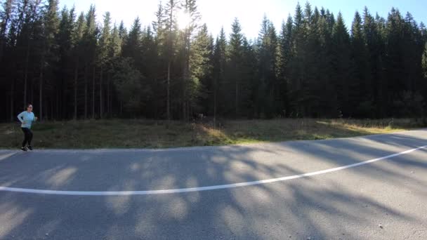 緑豊かな森を背景に田舎道を走る若い白人女性 — ストック動画