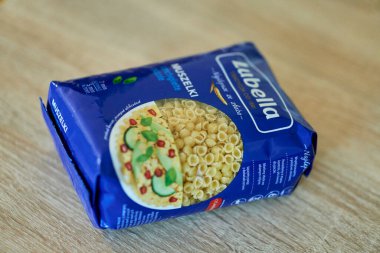 Plastik bir torba ile yakın plan bir fotoğraf. Arkaplanı bulanık, ahşap bir masa üzerinde Polonya Lubella marka makarna. Poznan, Polonya