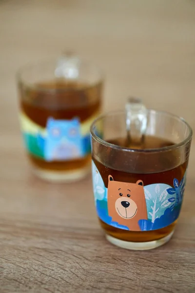 A selective focus shot of the two tea glass mugs with tan animal drawing