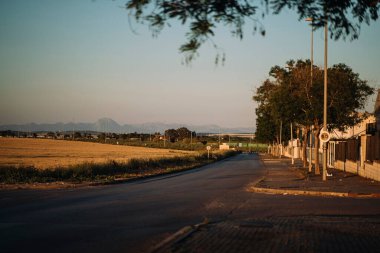 Trafik işaretleri ve solunda tarım arazileri olan boş uzun bir yol.