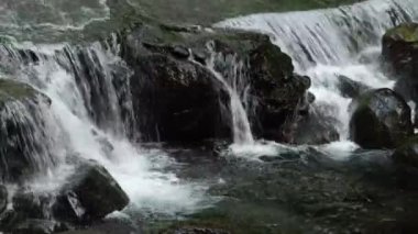 Kayaların arasından geçen güzel bir şelale manzarası.