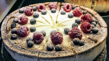 Cheesecake 'in üzerindeki lezzetli yaban mersinli ahududu parçalarının yakın plan çekimi.