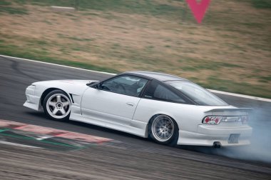 Beyaz Nissan Silvia S13 yarış pistinde sürükleniyor