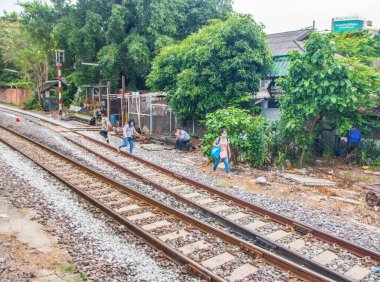 Tayland 'ın güneydoğusundaki Bangkok banliyösündeki bir tren istasyonunun raylarındaki Taylandlılar