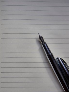 Boş bir kağıt üzerindeki eski mürekkep kaleminin dikey görüntüsü.