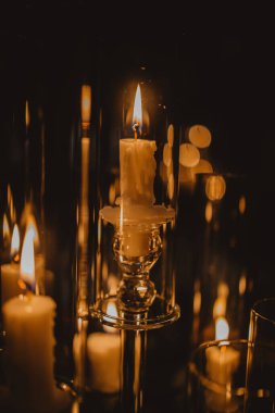 Şeffaf bir şamdanda yanan bir mumun dikey görüntüsü.