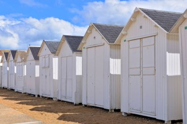 A beautiful shot of white cottages in a line on a beach under cloudy sky