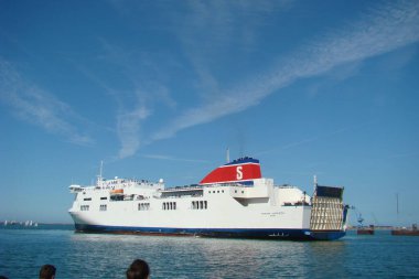 A scenic view of a ship sailing in the blue seascape near the harbor of Cherbourg, France