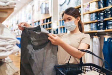 A Thai woman wearing a protective face mask buying clothes in a store