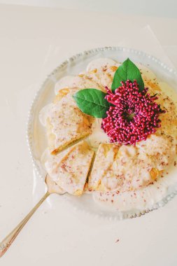 A vertical, top view of a round cake decorated with a purple flower