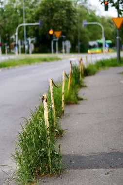 A vertical view of a barrier with short rusty poles and green grass