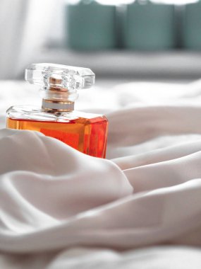 Bulanık bir arkaplanda beyaz bir bez arasında lüks bir kadın parfüm şişesinin dikey çekimi..