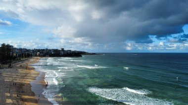 A panoramic view of a beautiful green colored sea's foamy waves hitting the seashore