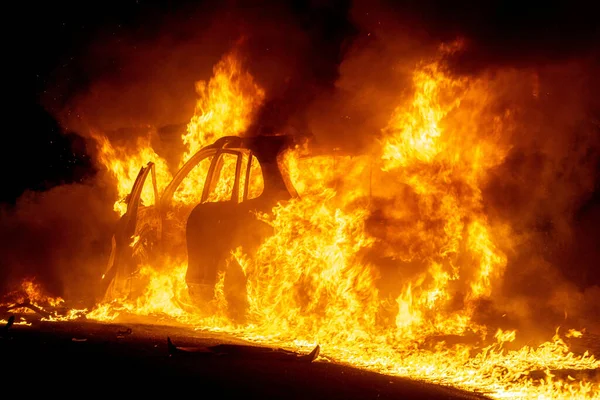 A fire emergency in a forest with a car caught in red fire flames