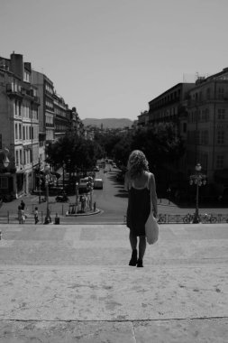 A grayscale of a female walking in a park on a sunny day