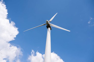 Mavi bulutlu gökyüzüne karşı yel değirmeninin alçak açısı