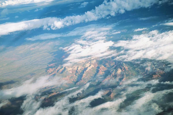 An aerial view of mountains under a cloudy sky