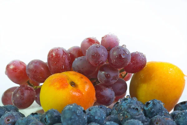fresh mixed fruits like red grapes, apricots and blueberries, white background. Concept: healthy fresh fruit