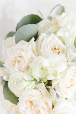 A vertical view of a beautiful bouquet of white roses with green leaves