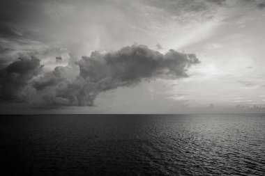 A grayscale shot of cloudy sky over the sea