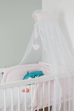 A vertical shot of a cradle in a baby girl's nursery