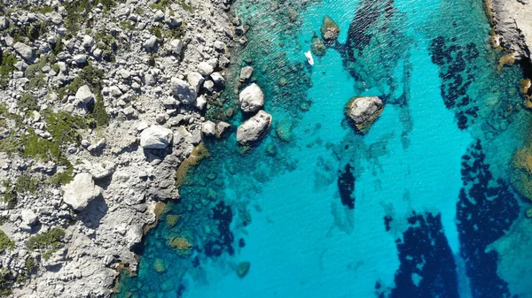 A top view of small rocks with green moss and turquoise water