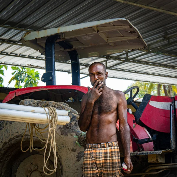 Black Male Standing Front His Red Tractor Smoking Cigarette — Stok fotoğraf