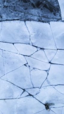 A flipped vertical shot of cracked flooring texture in gray tones