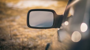 A small side-view mirror of a car in a blurred background