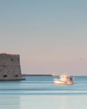 Gün batımında kalesi olan kıyıya yakın bir tekne.