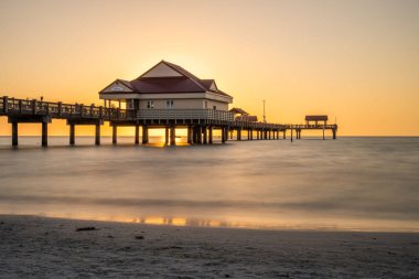 Manzaralı gün batımında deniz kenarında bir evin olduğu büyüleyici bir deniz manzarası.