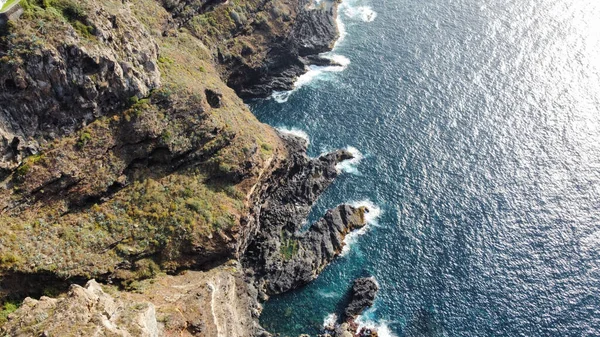 An aerial view of high coastal cliffs and the ocean on a sunny day