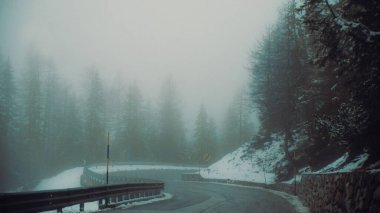 A foggy, curvy road in the snowy forest in South Tyrol, Italy